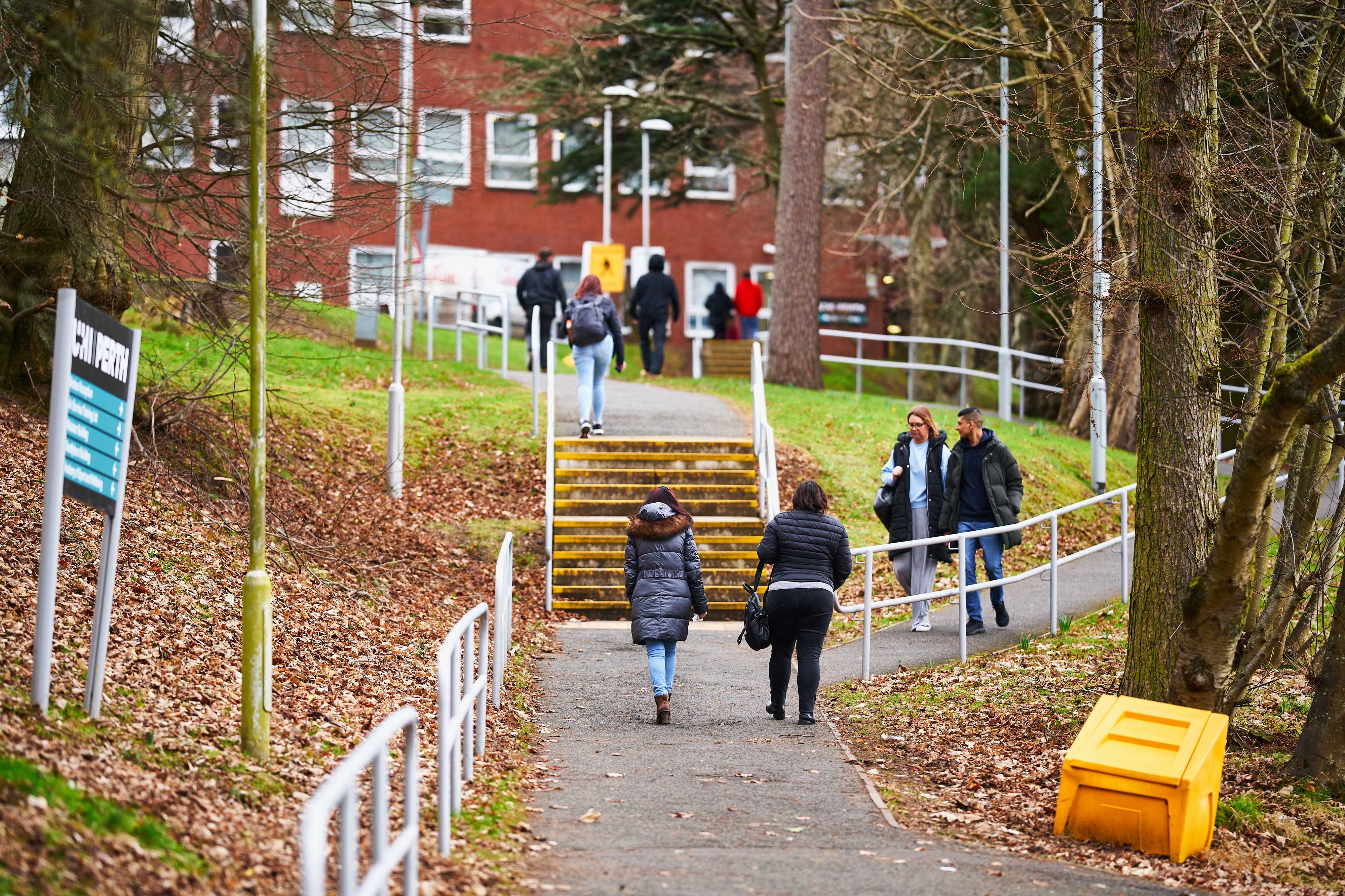 Scene of leafy campus and students walking up path