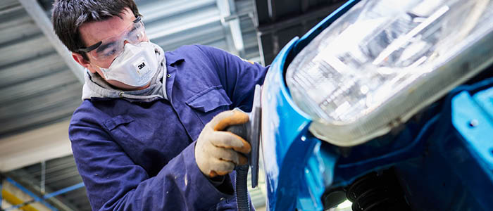 student sanding down vehicle bodywork