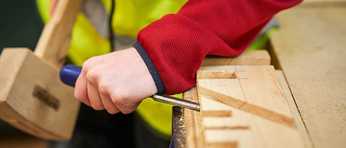 student using chisel on wood