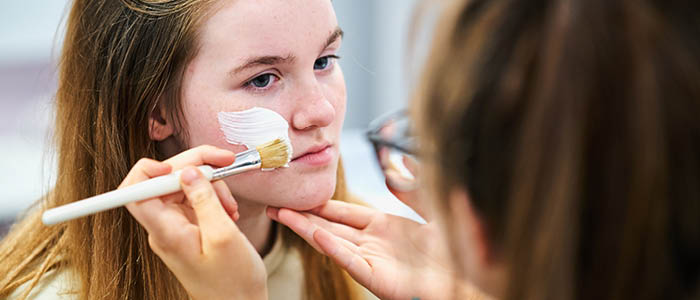 student applying make-up to another student