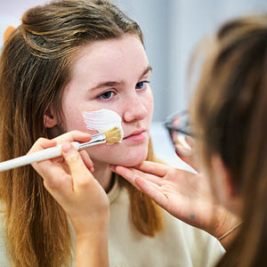 student applying make-up to another student