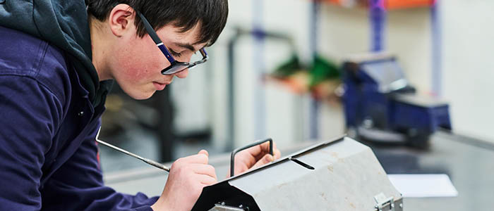 student marking up sheet metal