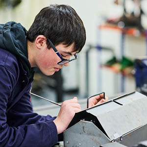 student marking up sheet metal