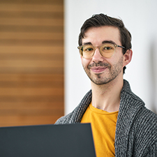 Ian standing holding a laptop